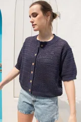 Saco tejido de punto calado con mangas al codo, cuello redondo y cierre frontal con botones de coco. Presenta un diseño versátil y ligero.
