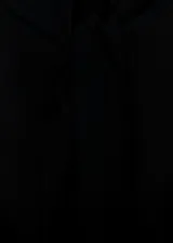 Vestido corto negro sin mangas, con cuello alto tipo halter y detalle de panel semitransparente en el frente. Presenta un diseño recto y cierre de lazo en la parte posterior del cuello.