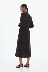 Vestido midi de manga larga en color marrón, con cuello mao abierto, cierre frontal con botones ocultos, puños abotonados y cinturón ajustable para anudar en la cintura.