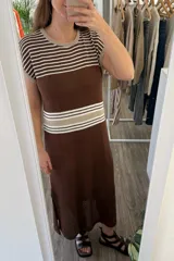 Vestido largo tejido color marrón con rayas horizontales beige y blancas en la parte superior, detalle calado en la parte inferior y tajos a los costados.