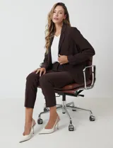 Blazer sastrero entallado color beige, con cuello de solapa, cierre frontal con un botón a tono y hombreras estructuradas. Presenta bolsillos laterales con solapa y forro interno.