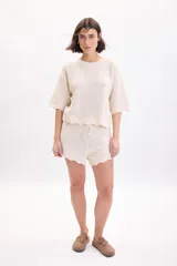 Short tejido de punto con diseño fantasía en color crudo, con cintura elástica y cordón ajustable.