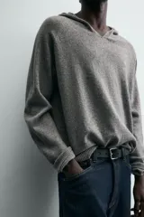 Jersey de lana gris, corte regular, con cuello pico que incorpora una capucha y manga larga. Presenta acabados en rib en puños y bajo.