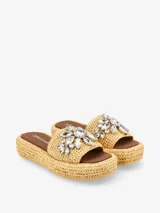 Sandalias tipo plataforma con base de acabado trenzado y capellada ancha decorada con apliques de diseño floral.