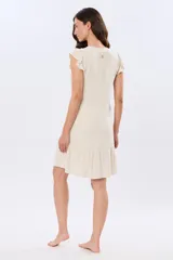 Vestido corto color beige con escote en V, sin mangas con volados en los hombros y cierre frontal de botones. Cuenta con falda con volado en el ruedo.