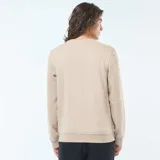 Buzo color beige liso de cuello redondo y manga larga con puños y ruedo acanalados.