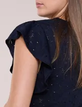 Blusa blanca de tejido calado estilo broderie con escote en V y mangas cortas tipo mariposa.
