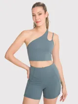 Top deportivo asimétrico de un hombro con diseño de tirante fino adicional y apertura frontal. Confeccionado en tejido técnico con sujetador integrado y almohadillas removibles.