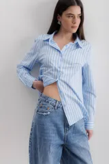 Camisa de corte clásico con cuello camisero, manga larga con puños abotonados y cierre frontal con botones. Presenta un diseño de rayas verticales finas en color negro sobre fondo blanco.