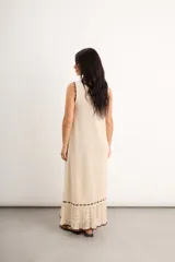 Vestido largo de punto color bordó con diseño sin mangas, cuello redondo y detalles de ribete en color celeste en el cuello, sisas, ruedo y a lo largo de la parte inferior, culminando en un acabado calado con volados.