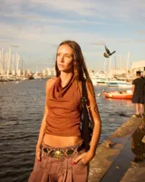 Cartera tipo baguette de gamuza color chocolate, con diseño decorado con diversos apliques metálicos, perlas y piezas de piedra. Cuenta con cierre superior y correa ajustable.