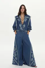 Jean wide leg de denim azul con elástico en la cintura, cordón ajustable y bordados decorativos en los laterales.