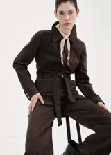 Enterito largo de algodón estilo tejano, color marrón, con cuello camisero, mangas cortas, cierre frontal con cremallera y cinturón ajustable en la cintura.