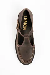 Zapato tipo guillermina de cuero lavado color marrón, con diseño de tira en T y cierre de hebilla metálica. Presenta costuras decorativas en contraste y suela de goma con plataforma dentada.