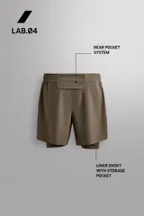 Short de running 2 en 1 color beige, confeccionado en tejido técnico ligero y elástico con malla interior integrada. Presenta cintura elástica ajustable con cordón, bolsillo trasero con cierre y aberturas laterales en el bajo.