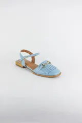 Sandalias de cuero color celeste, con punta cerrada, flecos frontales y detalle de estribo metálico dorado. Tienen tira ajustable al tobillo y suela plana con pequeño taco.