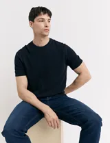 Remera de punto color beige, de manga corta y cuello redondo.