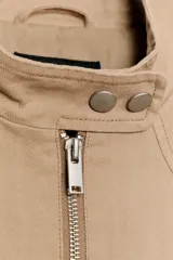 Chaqueta de cuello subido y manga larga, con cierre frontal de cremallera y botones a presión. Presenta bolsillos de vivo en el delantero y forro interior combinado.