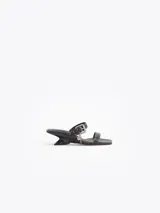 Sandalias de cuero vacuno efecto gastado color negro, con taco de 4 cm, tiras con mini tachas, hebilla metálica y dijes colgantes.