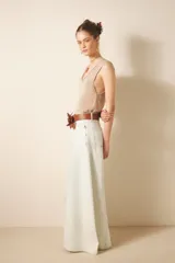 Jean de tiro alto y corte ultra ancho, confeccionado en denim rígido con lavado bleach que le otorga un tono casi blanco. Presenta recortes estratégicos en las piernas y el tiro, brindando una silueta con gran vuelo y movimiento. Incluye cierre y botón frontal, además de forrería interna estampada.