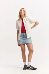 Camisa de manga corta color blanco marfil con textura y mangas abullonadas. Tiene cuello camisero, calce suelto y cierre frontal con botones.