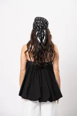 Top negro de diseño versátil con tirantes finos, silueta abombada, elástico en la espalda y hebilla forrada en el frente.