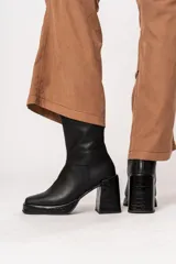 Bota de caña media color negro, de cuero, con horma cuadrada, taco geométrico con textura símil cocodrilo y plataforma.