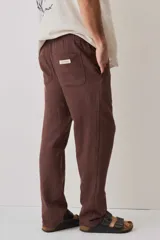 Pantalón de tiro medio con cintura elástica y cordón ajustable, textura tejida, corte recto y silueta amplia.