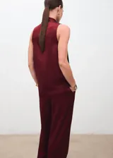 Blusa de satén color bordó con cuello drapeado y detalle de fular integrado que se sujeta en el hombro. Diseño sin mangas con tirantes anchos y corte recto.
