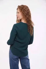 Blusa verde con cuello en V y mangas largas.