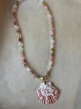 Collar largo de cuentas de piedras semipreciosas en tonos tierra, con dijes de conchas marinas.