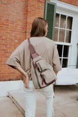 Bandolera de cuero color beige con detalles en bordó. Tiene correa ancha regulable para llevar cruzada al cuerpo, cierre principal con cremallera y dos bolsillos frontales con cierre.