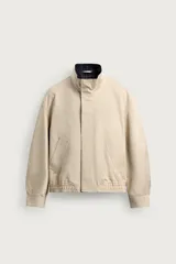 Cazadora regular fit de algodón color beige, con cuello subido y forro interior a contraste con estampado de cuadros. Cuenta con manga larga con puño abotonado, bolsillos de vivo en la cadera y cierre frontal de cremallera oculta por solapa con botones a presión.