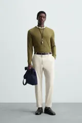 Pantalón chino de algodón color crema, corte regular fit, con cierre frontal de cremallera y botón, bolsillos delanteros y bolsillos traseros de vivo con botón.