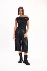 Top negro con estampado tartán, escote off-shoulder, mangas cortas y detalle de tachas plateadas en el escote.