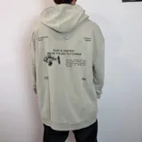 Canguro oversize color beige con capucha y estampado gráfico en la espalda que incluye un esqueleto de pez y texto descriptivo.