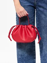 Bolso de mano tipo saco o 'balloon' de cuero sintético color rojo vibrante, con cordón ajustable en la parte superior y asas cortas.