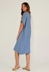 Vestido midi de lino color beige, con cuello en V, cierre frontal parcial con botones y mangas cortas con dobladillo.