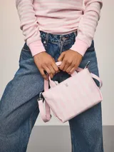 Mini bolso bandolera Victoria's Secret con diseño de rayas verticales en tonos rosados, asas cortas de mano y correa ajustable y extraíble.