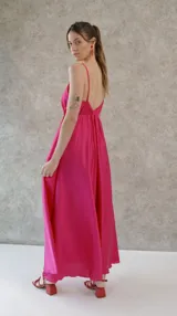 Vestido solera largo de seda color fucsia, con escote en V pronunciado en el frente y la espalda, y cintura elastizada.