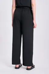 Pantalón negro de corte palazzo con lazo en la cintura y textura arrugada.