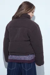 Campera puffer de corderito negro con cuello alto y diseño oversized. Presenta una textura tipo teddy, cierre frontal y corte a la cintura.