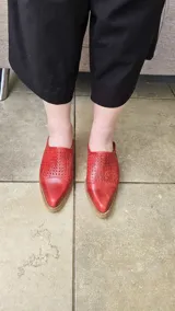 Zapatos destalonados de cuero color tostado, con perforaciones en el empeine y cierre lateral con hebilla metálica.