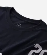 Remera deportiva de corte oversized, color negro, con estampado gráfico en la espalda del equipo Las Vegas Raiders de la NFL. Presenta cuello redondo, mangas cortas con detalles de rayas blancas y logo de la NFL en la parte superior trasera.