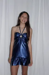 Vestido corto azul metalizado con diseño cut-out, argolla central en el busto, tirantes halter y falda con volado en el ruedo.
