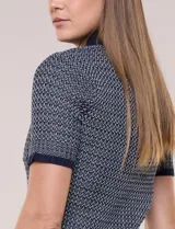 Cardigan de punto con textura Jacquard, cuello camisero, manga corta y cierre frontal con botones metálicos. Presenta bolsillos decorativos en el pecho.