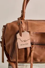 Cartera de cuero color negro con efecto lavado y desgastado, estilo vintage. Cuenta con múltiples bolsillos con cierre delantero, tiras colgantes y doble asa corta de mano.