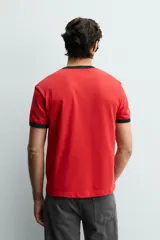 Camiseta de corte regular color rojo con cuello redondo y bordes de mangas en color azul marino. Presenta una estampa frontal con la frase 'The Best Plan.' en color azul marino.