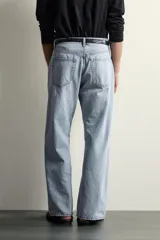 Jeans de denim de algodón en color azul con efecto desgastado, tiro medio y corte recto de ajuste holgado (loose fit). Cuenta con diseño clásico de cinco bolsillos y cierre frontal con cremallera y botón.