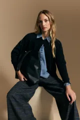 Cardigan de tejido de punto color negro, con cierre frontal de botones, cuello redondo y puños acanalados.